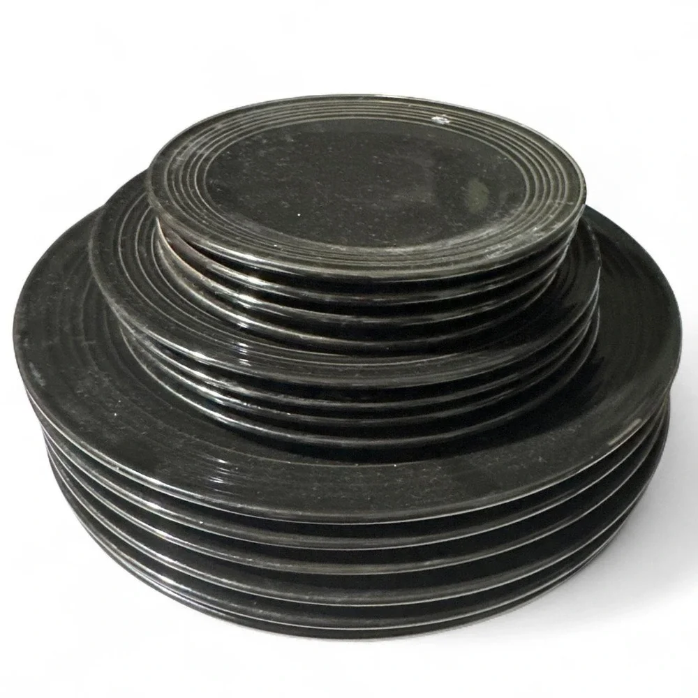 Black dish-ware plate set with concentric ridges.